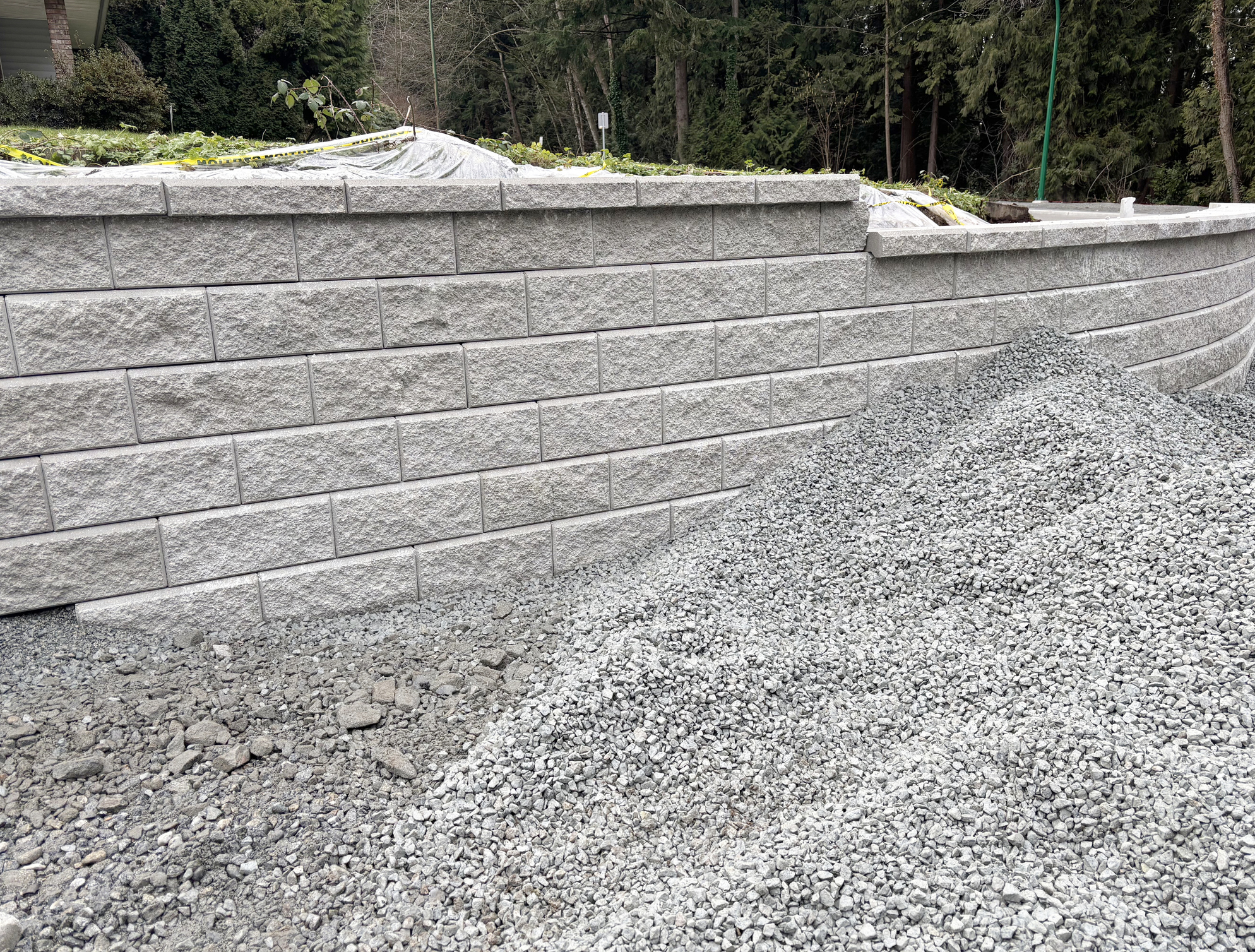 Segmental block retaining wall with drainage gravel backfilled behind it.