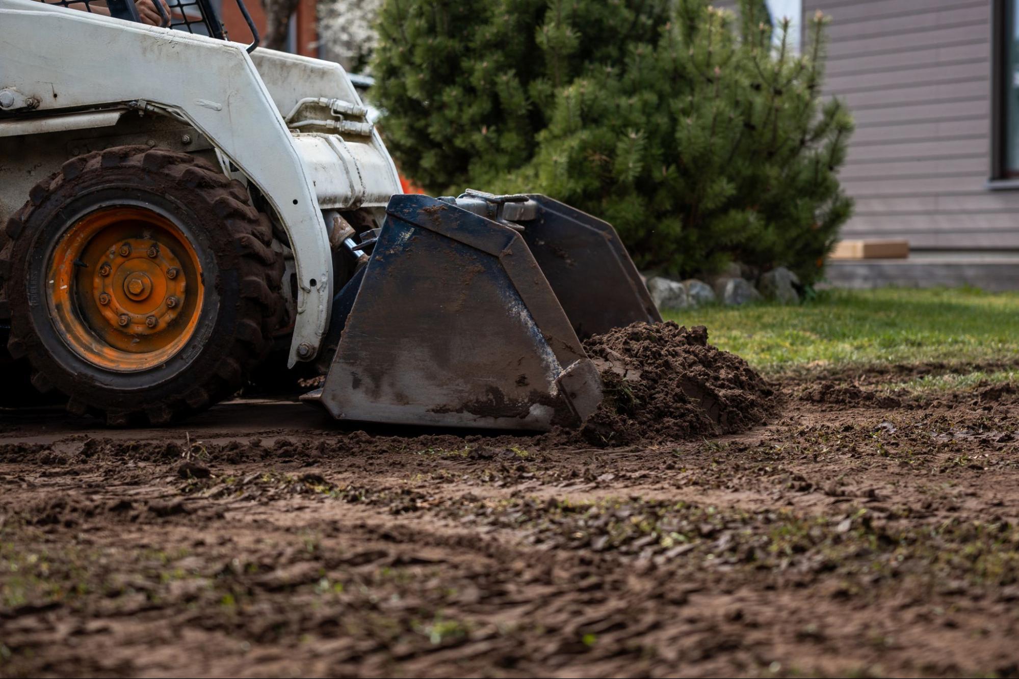 Skid steer fine grading a yard to prepare soil for sod.