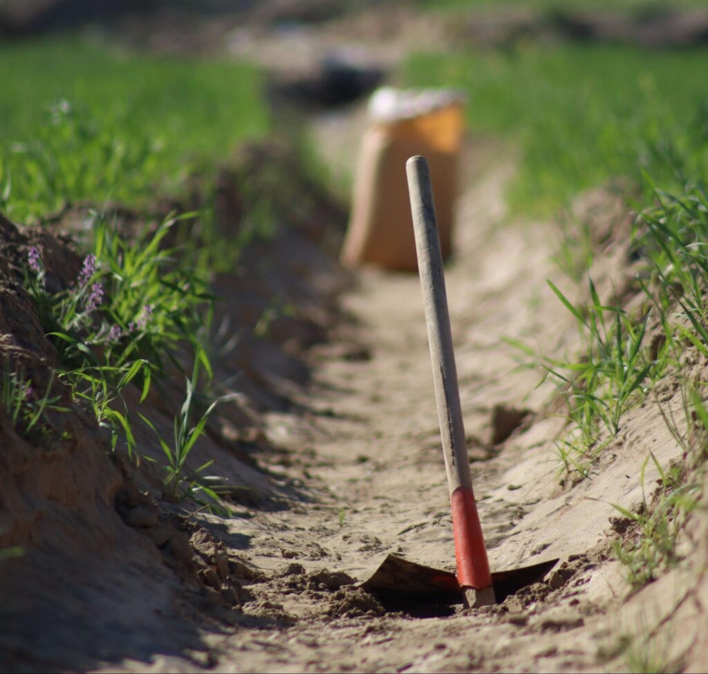 Shovel standing in a freshly dug trench cut through a grassy yard, a common first look at utility trenching in Boise, ID